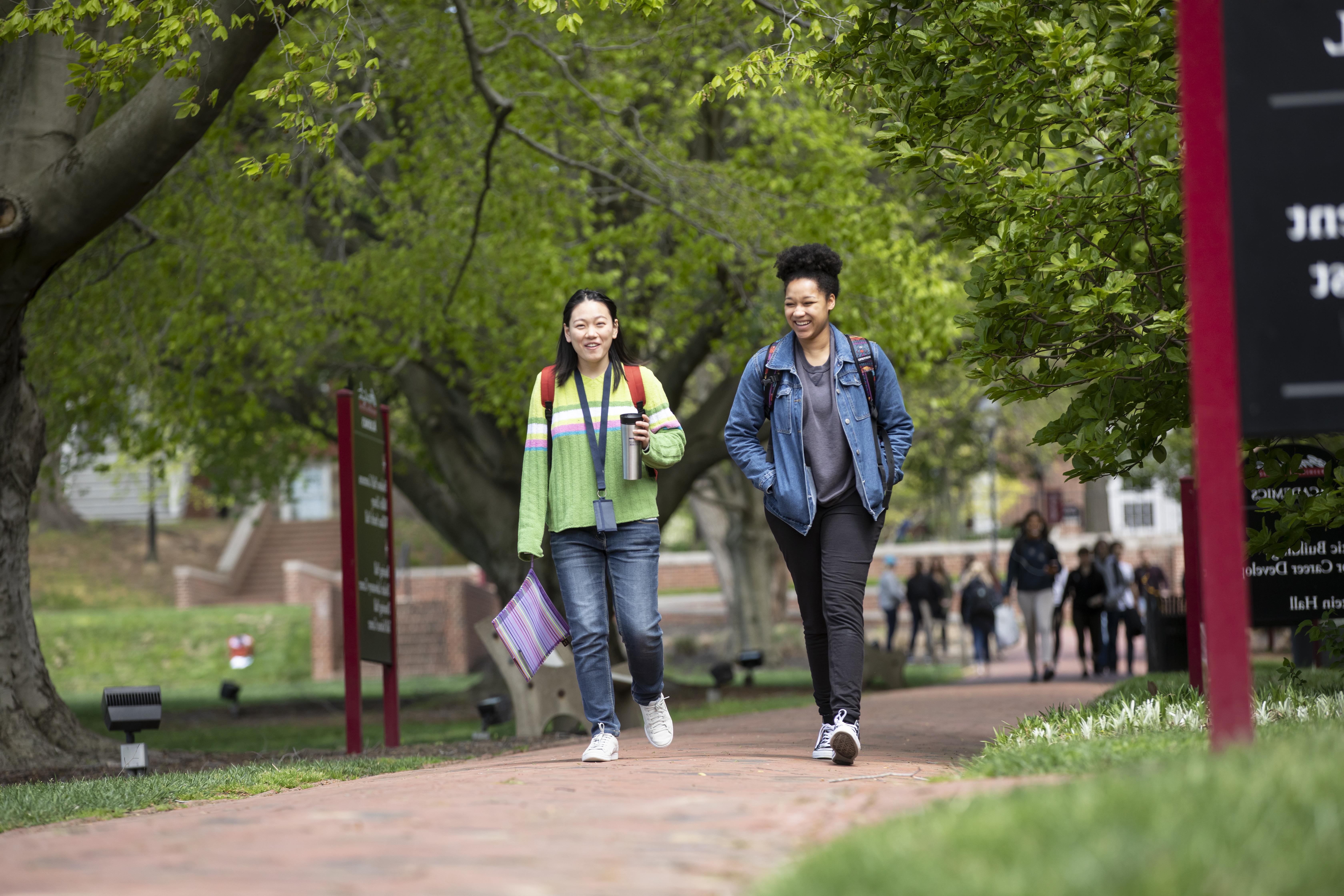 Two Washington College students walk and smile 