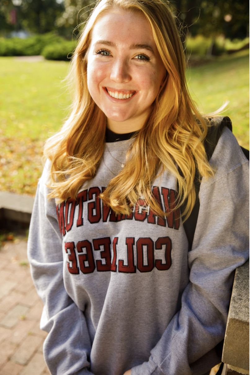 Haley, smiling and wearing a grey hoodie with "Washington College" in red lettering. 